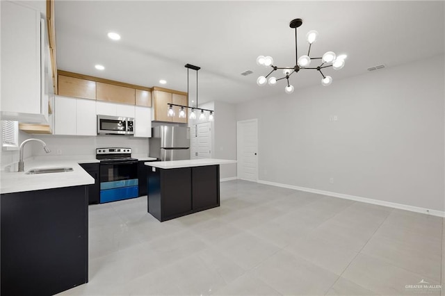 kitchen with pendant lighting, sink, appliances with stainless steel finishes, white cabinetry, and a kitchen island