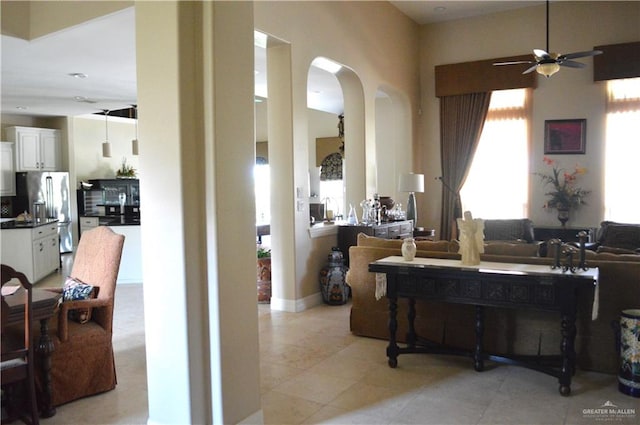 interior space featuring light tile patterned floors, a towering ceiling, and ceiling fan