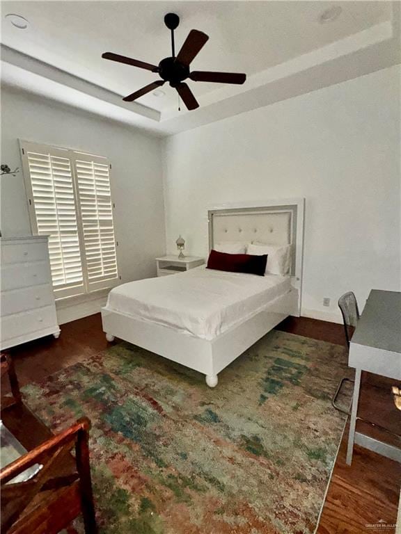 bedroom featuring a raised ceiling, ceiling fan, and dark wood-type flooring