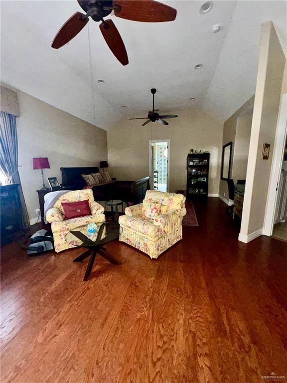 living room featuring lofted ceiling, ceiling fan, and dark wood-type flooring