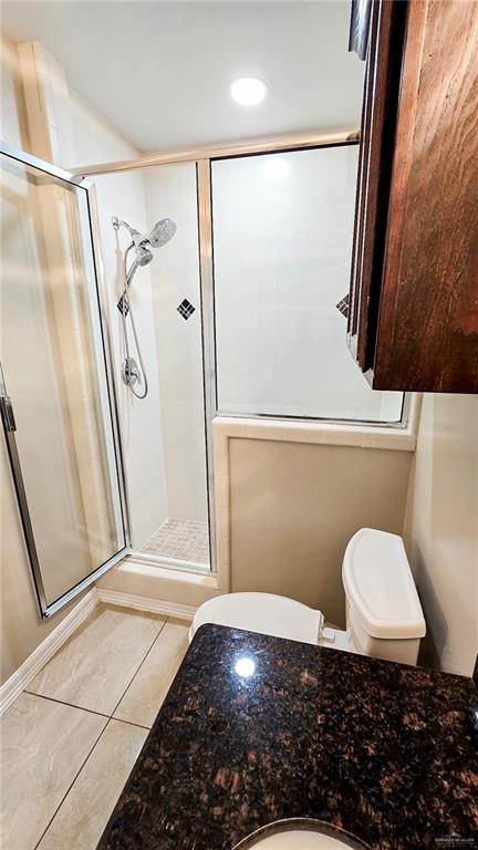 bathroom with tile patterned floors, toilet, and walk in shower