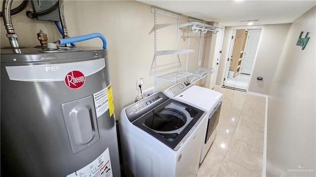 washroom with washing machine and clothes dryer, electric water heater, and light tile patterned flooring