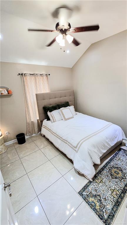 bedroom featuring ceiling fan, lofted ceiling, and light tile patterned floors