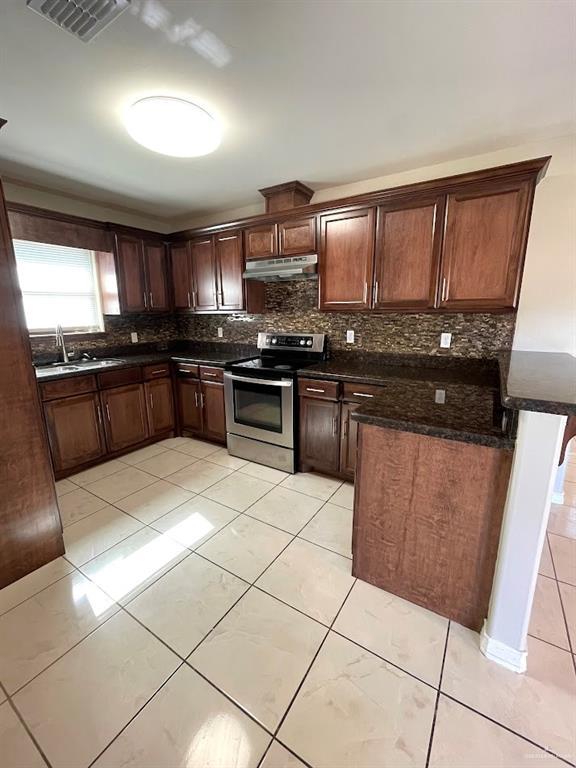 kitchen featuring visible vents, decorative backsplash, stainless steel electric stove, under cabinet range hood, and a sink