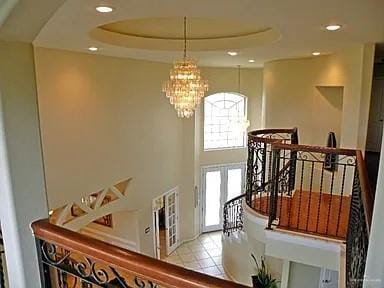 stairs featuring tile patterned floors, a tray ceiling, and an inviting chandelier