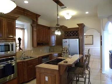 kitchen featuring decorative backsplash, sink, black appliances, decorative light fixtures, and a kitchen island