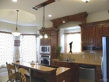 kitchen with sink, a center island, hanging light fixtures, wood counters, and appliances with stainless steel finishes