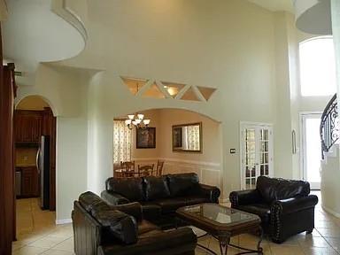 living room featuring a chandelier, a towering ceiling, and light tile patterned flooring