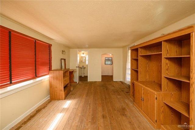 912 W Pierce Ave, Harlingen, TX 78550 - unfurnished living room with arched walkways, hardwood / wood-style flooring, and baseboards