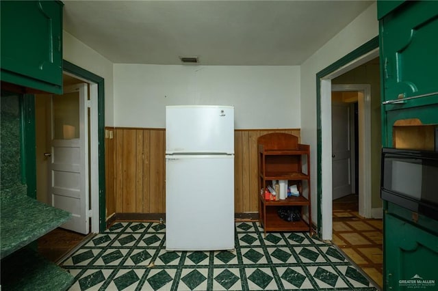 912 W Pierce Ave, Harlingen, TX 78550 - kitchen featuring freestanding refrigerator, a wainscoted wall, wood walls, tile patterned floors, and green cabinets