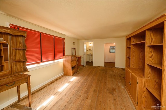 912 W Pierce Ave, Harlingen, TX 78550 - unfurnished living room featuring arched walkways, hardwood / wood-style floors, baseboards, and a sink
