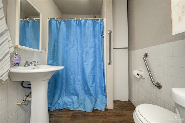 912 W Pierce Ave, Harlingen, TX 78550 - bathroom with tile walls, toilet, wood finished floors, a shower with shower curtain, and a sink