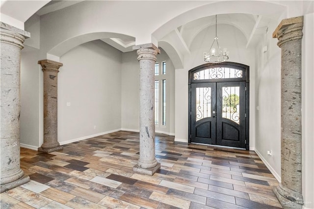 entryway with french doors, an inviting chandelier, dark hardwood / wood-style floors, and ornate columns