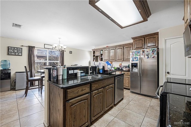 kitchen with sink, a kitchen island with sink, stainless steel appliances, light tile patterned flooring, and a chandelier