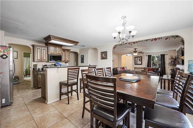 dining area with light tile patterned floors and ceiling fan with notable chandelier