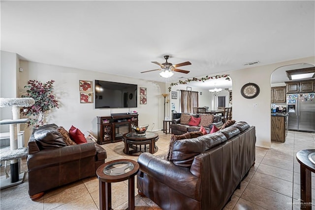 tiled living room featuring ceiling fan with notable chandelier