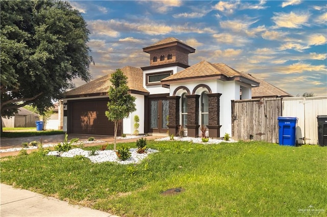 mediterranean / spanish home with driveway, fence, a yard, an attached garage, and stucco siding
