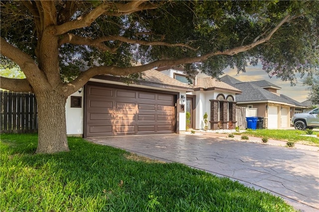view of front facade with a garage, fence, stucco siding, a shingled roof, and driveway