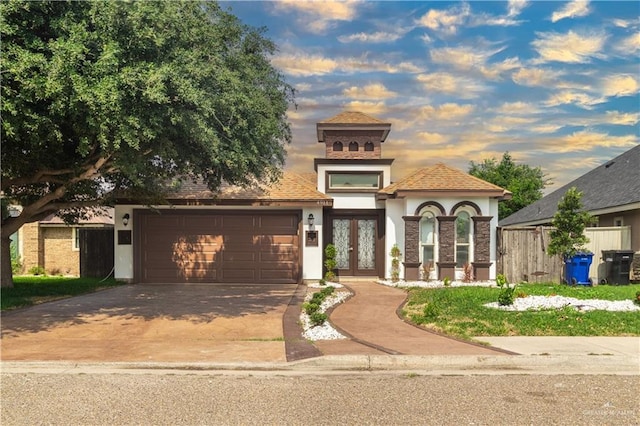 mediterranean / spanish house with an attached garage, stucco siding, french doors, and driveway