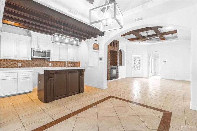 kitchen with stainless steel microwave, light tile patterned floors, white cabinets, and ceiling fan