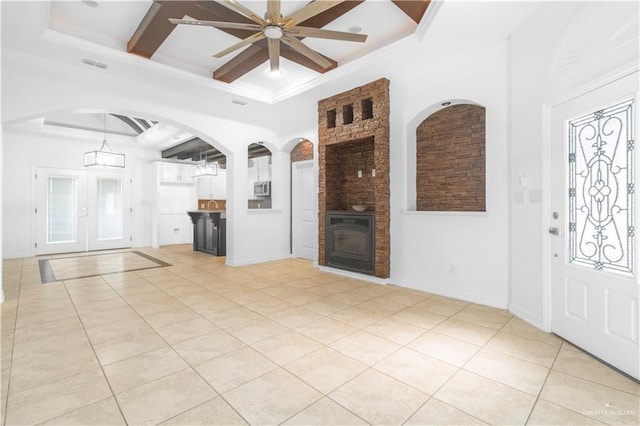 unfurnished living room featuring ceiling fan, visible vents, light tile patterned floors, and coffered ceiling