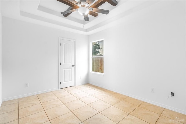 spare room featuring baseboards, ceiling fan, light tile patterned floors, and a raised ceiling