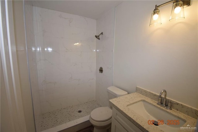 bathroom with vanity, toilet, and tiled shower