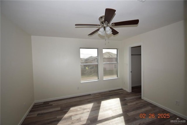 spare room with baseboards, wood finished floors, and a ceiling fan