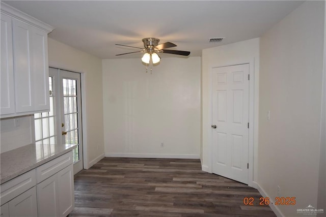 unfurnished dining area with visible vents, baseboards, ceiling fan, and dark wood-style flooring