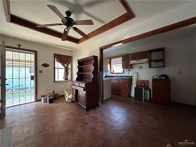 kitchen with ceiling fan, a tray ceiling, sink, and a healthy amount of sunlight