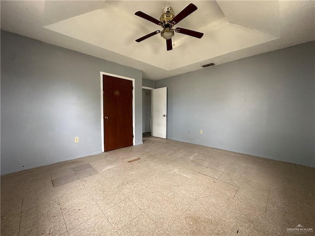 unfurnished bedroom featuring a raised ceiling and ceiling fan