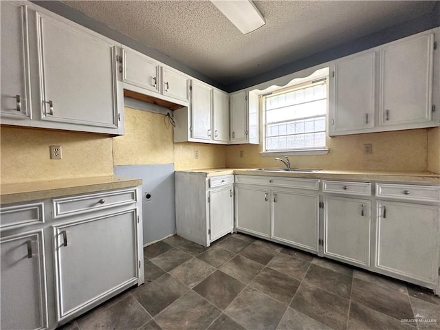 kitchen with white cabinetry, sink, backsplash, and a textured ceiling