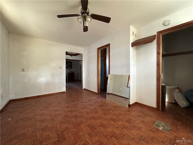 unfurnished bedroom with ceiling fan, a closet, and dark parquet floors