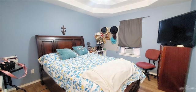 bedroom with a raised ceiling, light hardwood / wood-style flooring, and cooling unit