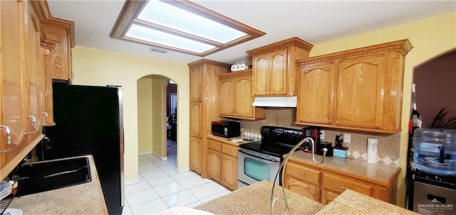 kitchen featuring backsplash, sink, light tile patterned floors, and black appliances