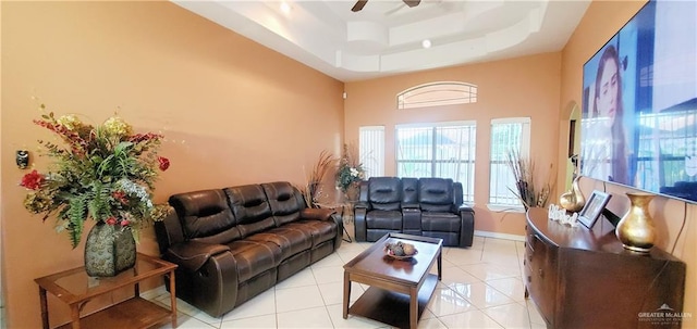 living room featuring ceiling fan, light tile patterned floors, and a tray ceiling