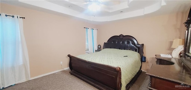 carpeted bedroom with a tray ceiling and ceiling fan