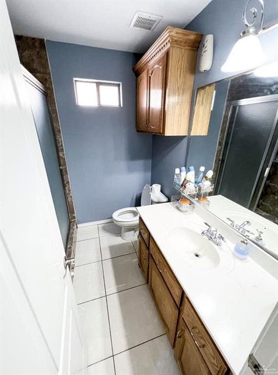 bathroom with tile patterned floors, vanity, toilet, and an enclosed shower