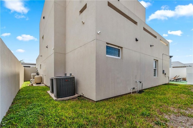 view of property exterior with a yard, fence, cooling unit, and stucco siding