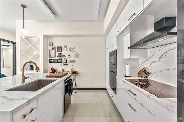 kitchen with a sink, white cabinets, black appliances, wall chimney exhaust hood, and pendant lighting