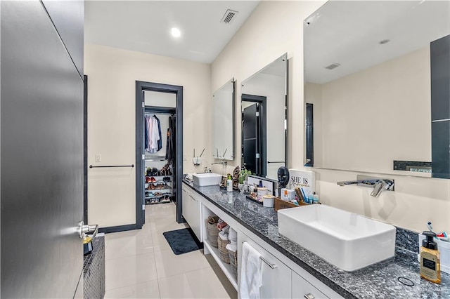 bathroom with a spacious closet, double vanity, a sink, and visible vents