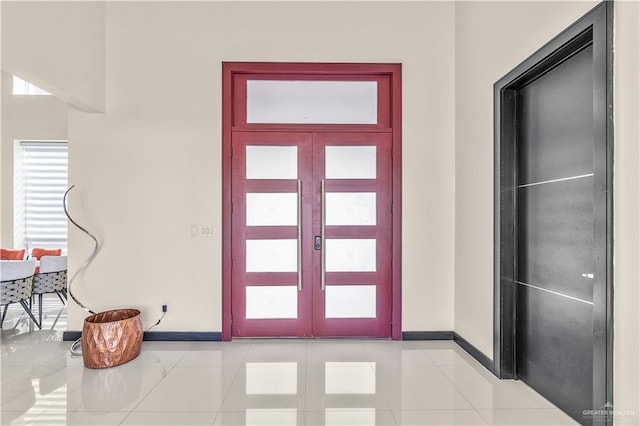 foyer entrance with french doors, light tile patterned flooring, and baseboards