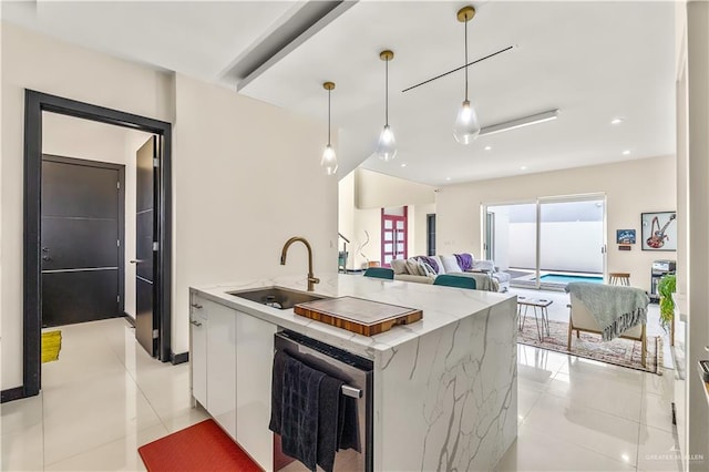 kitchen featuring pendant lighting, light tile patterned floors, a kitchen island with sink, white cabinets, and a sink