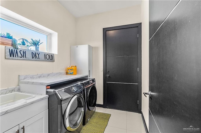 laundry area with washer and clothes dryer, light tile patterned flooring, a sink, and cabinet space