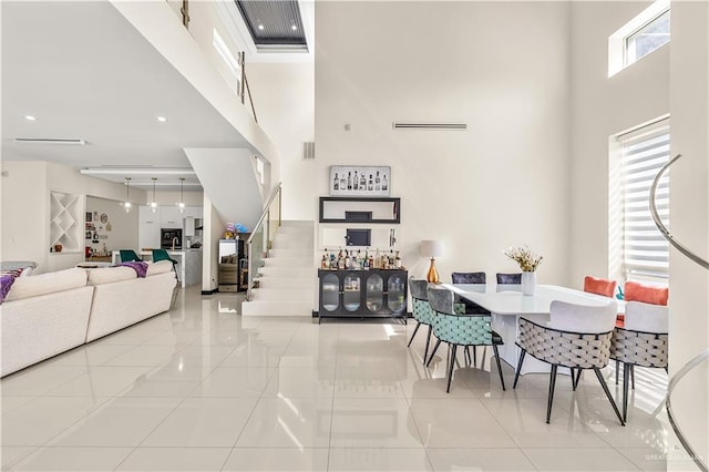 dining space with stairs, a high ceiling, and light tile patterned floors