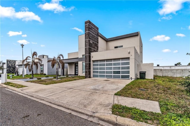 view of front of home with driveway, a front yard, an attached garage, and stucco siding