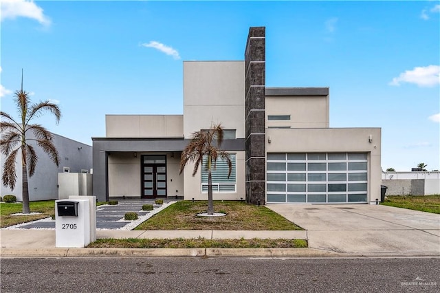 contemporary home with a garage, driveway, and stucco siding