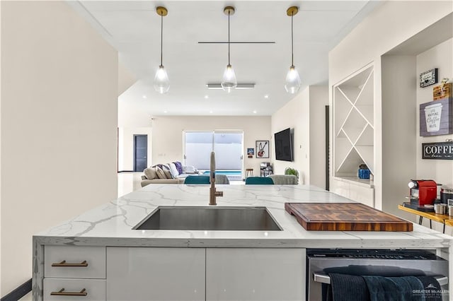 kitchen featuring open floor plan, white cabinets, hanging light fixtures, and a sink