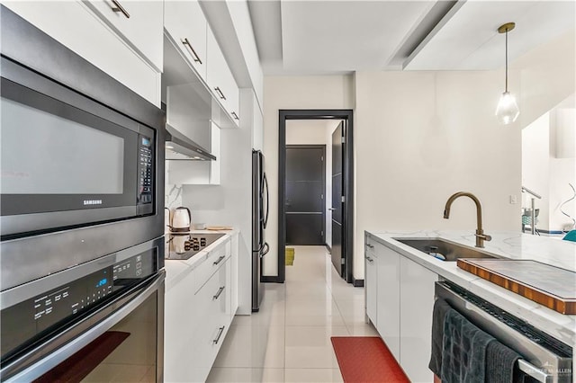 kitchen featuring white cabinetry, a sink, hanging light fixtures, and black appliances