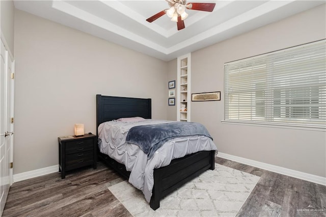 bedroom with hardwood / wood-style floors, a tray ceiling, and ceiling fan